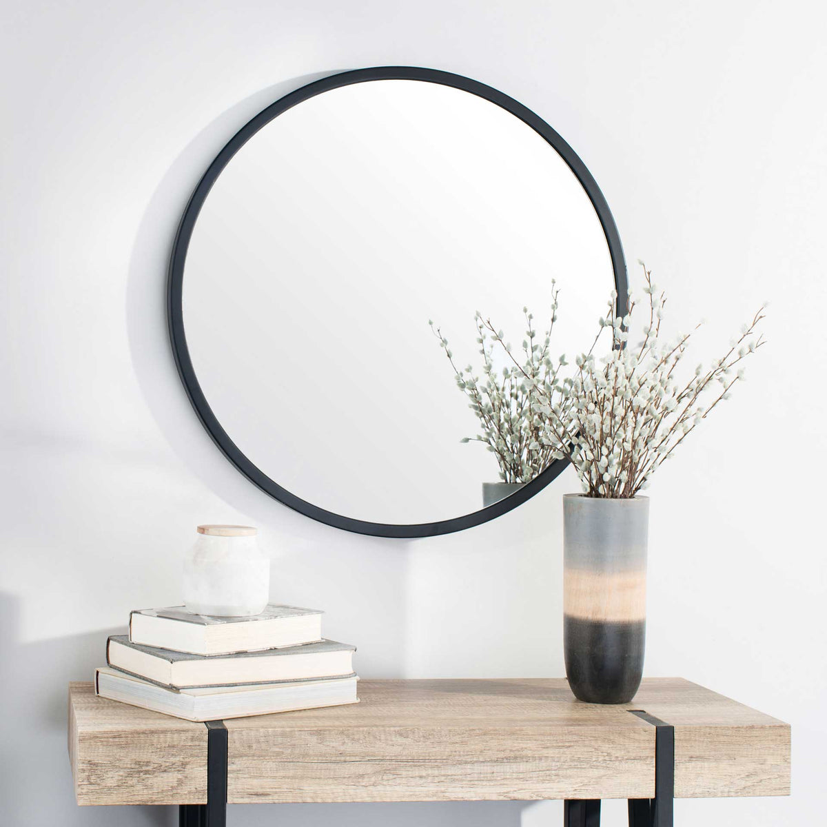 Black-framed round mirror adds contrast above a natural wood console.