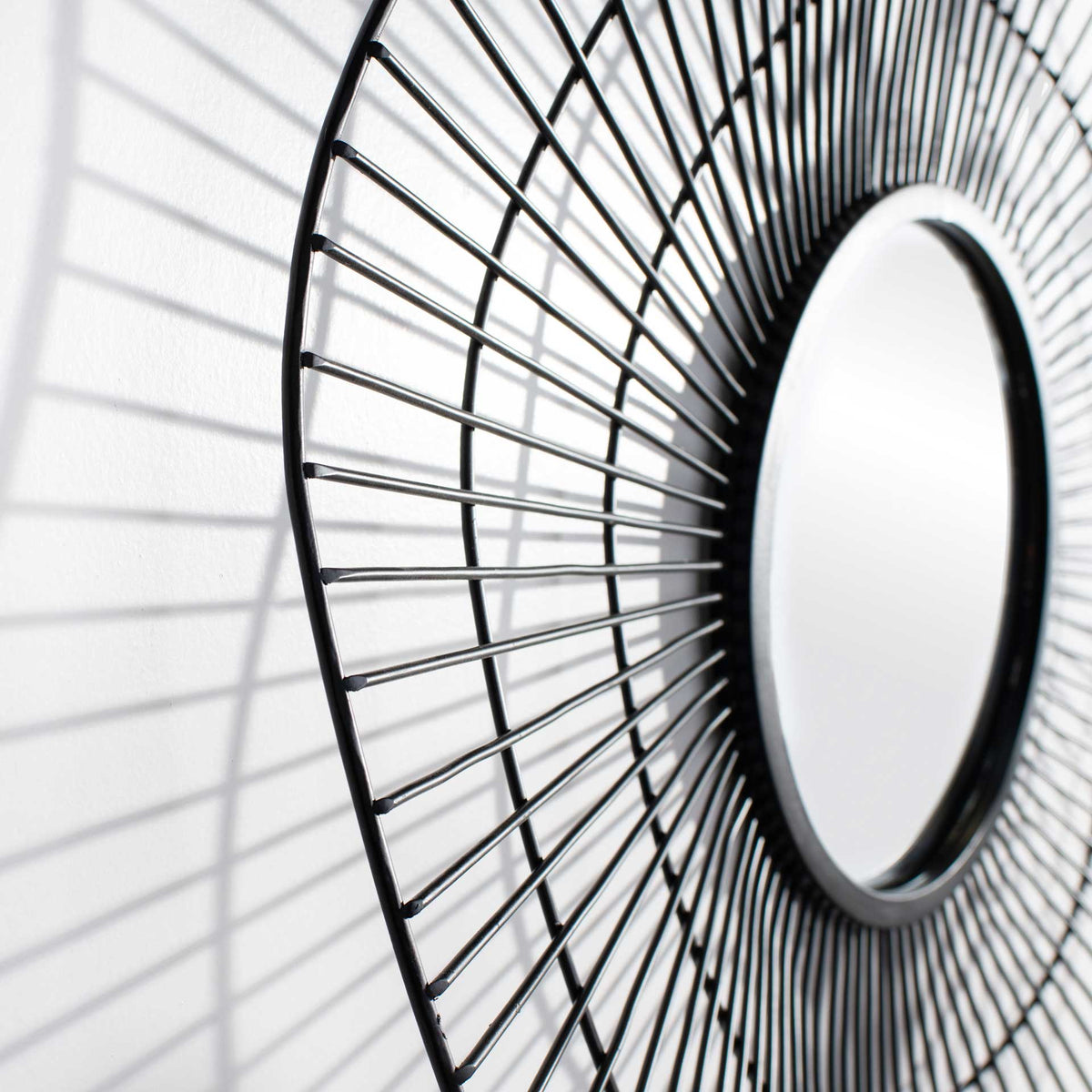 Fine wire spokes sweep toward a raised round mirror, creating a striking sense of depth.