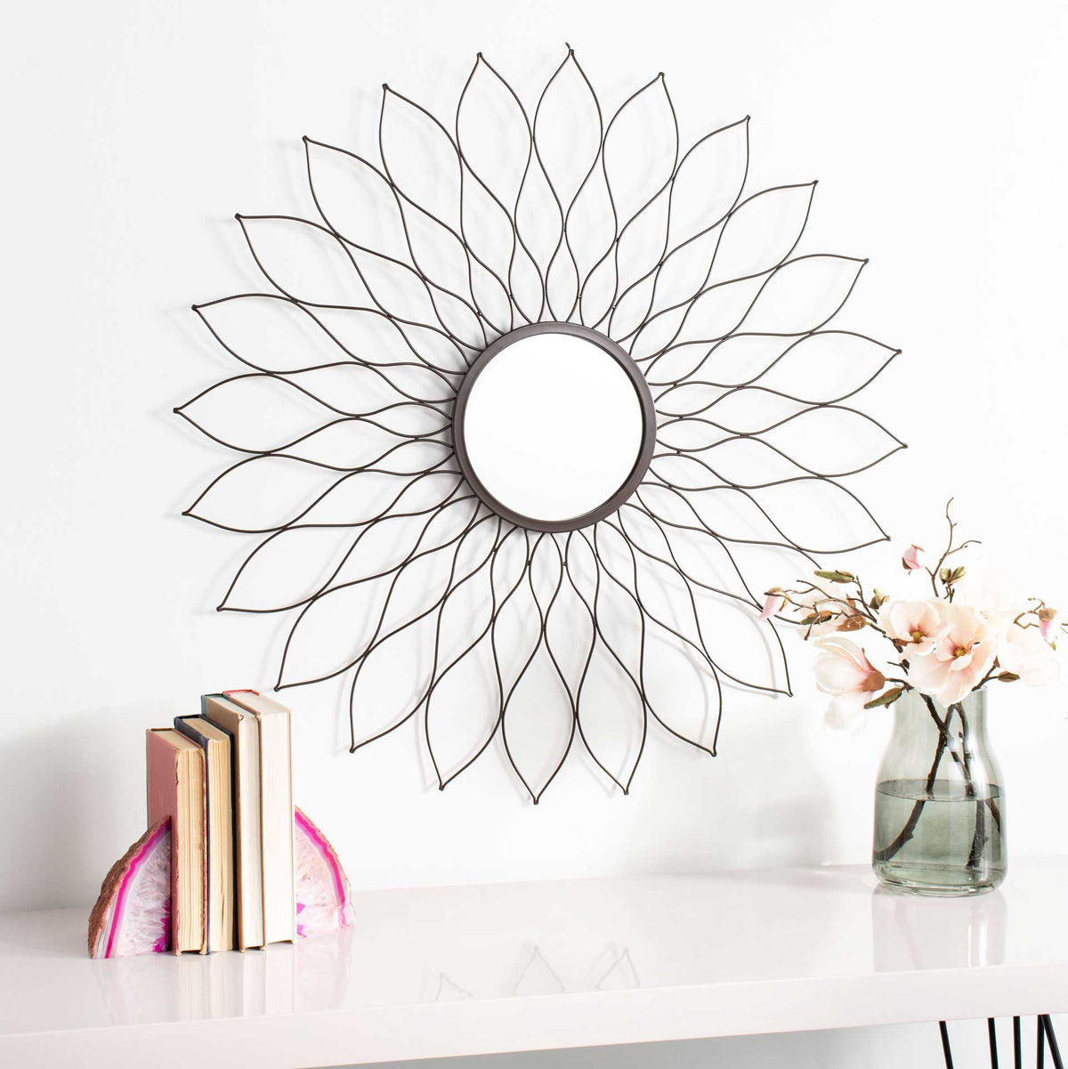 A circular mirror framed by sculptural, openwork petals adds a soft floral accent.