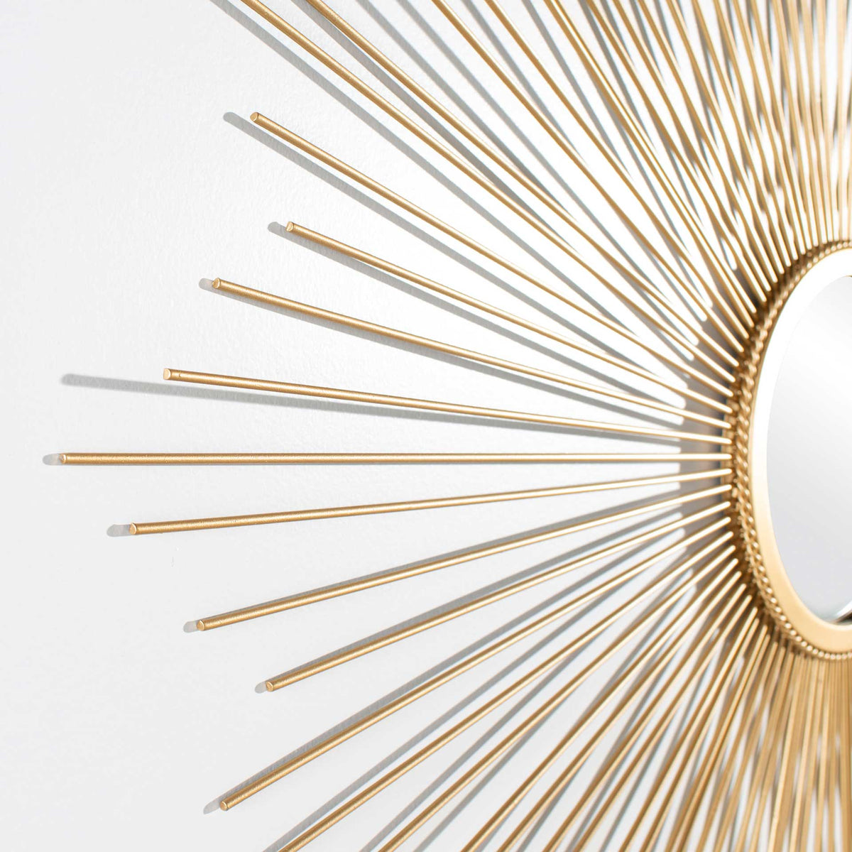 Slender gold rays flare from a textured ring around the round mirror.