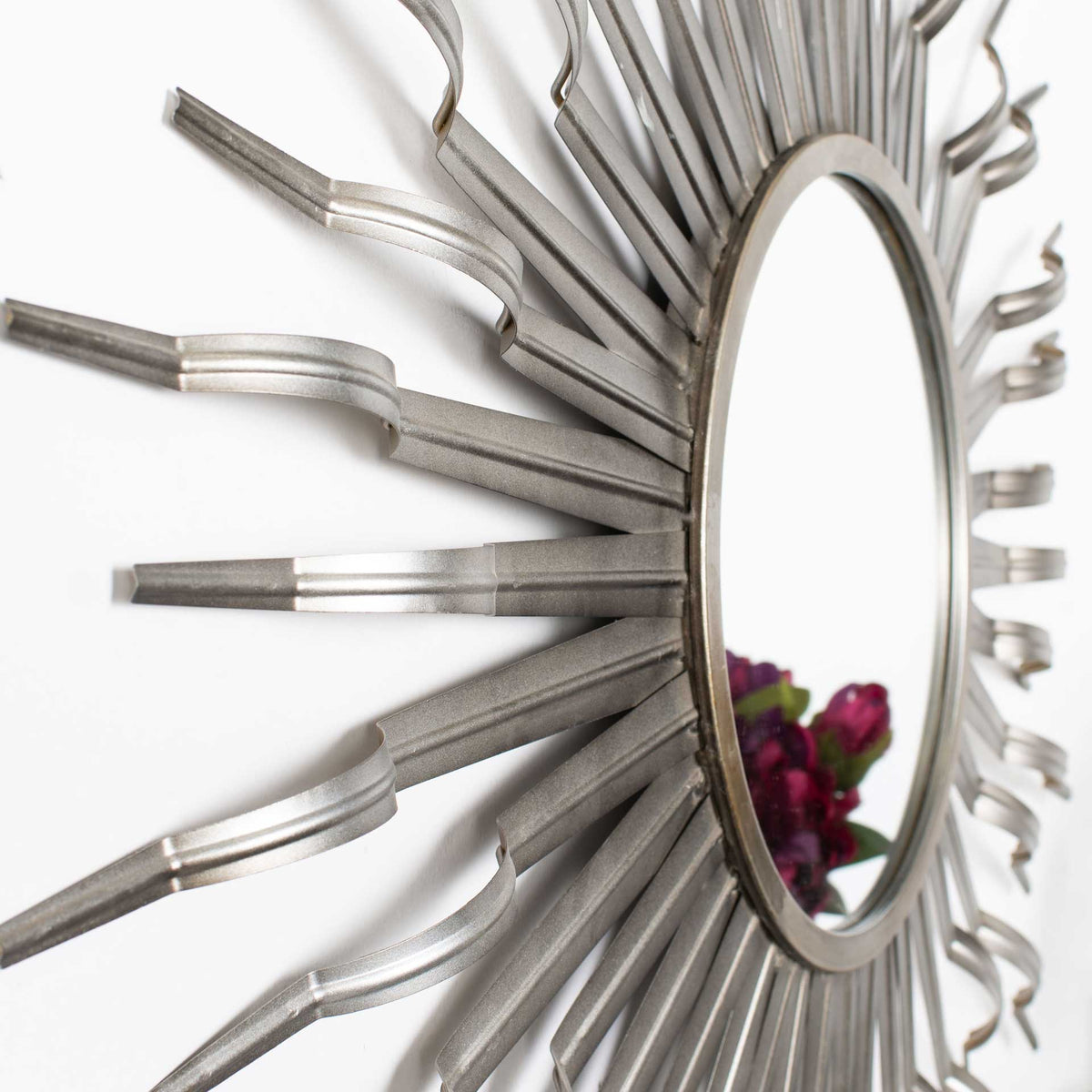 Curved gunmetal rays and a slim circular frame give the mirror sculptural depth