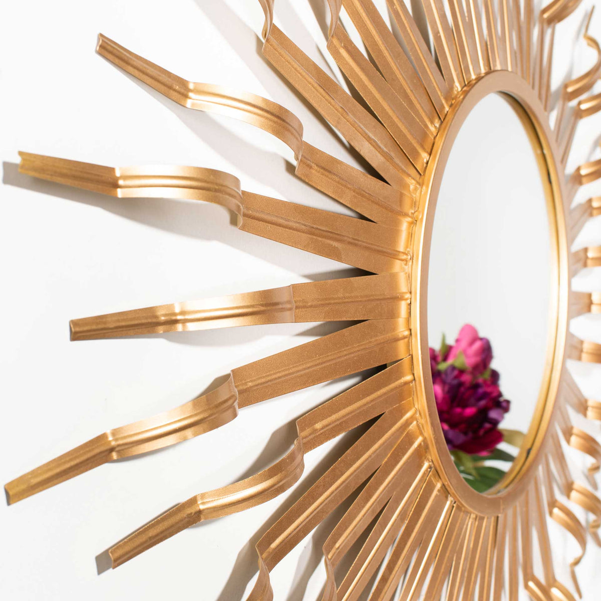 A slim gold mirror rim meets dimensional metal rays with a warm metallic sheen