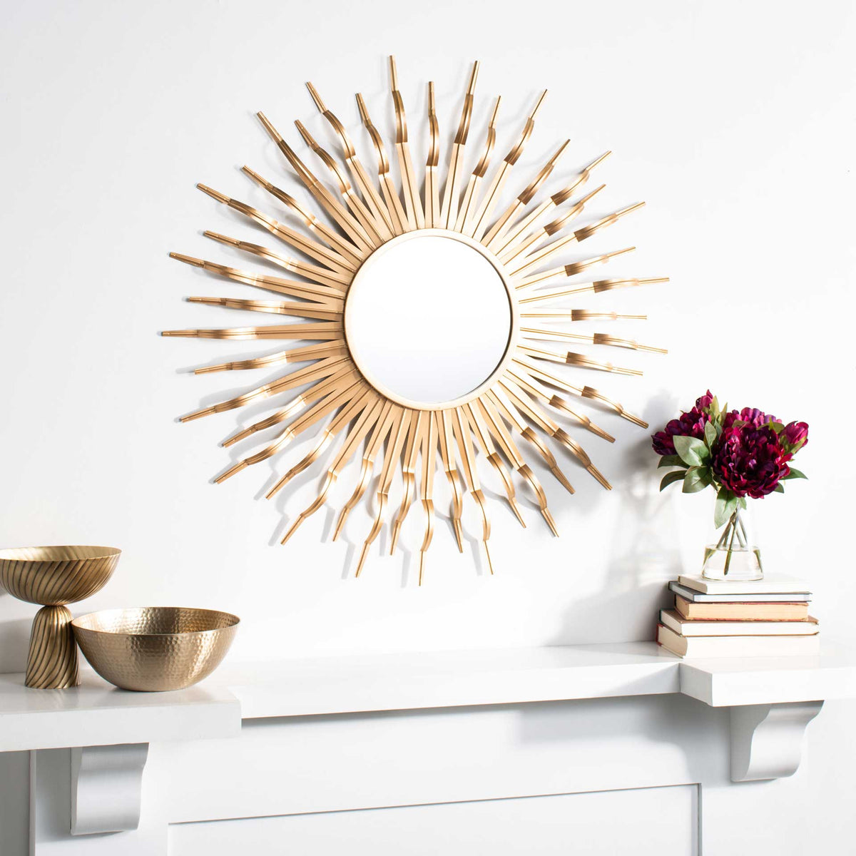 Gold sunburst mirror adds sculptural shine above a white mantel