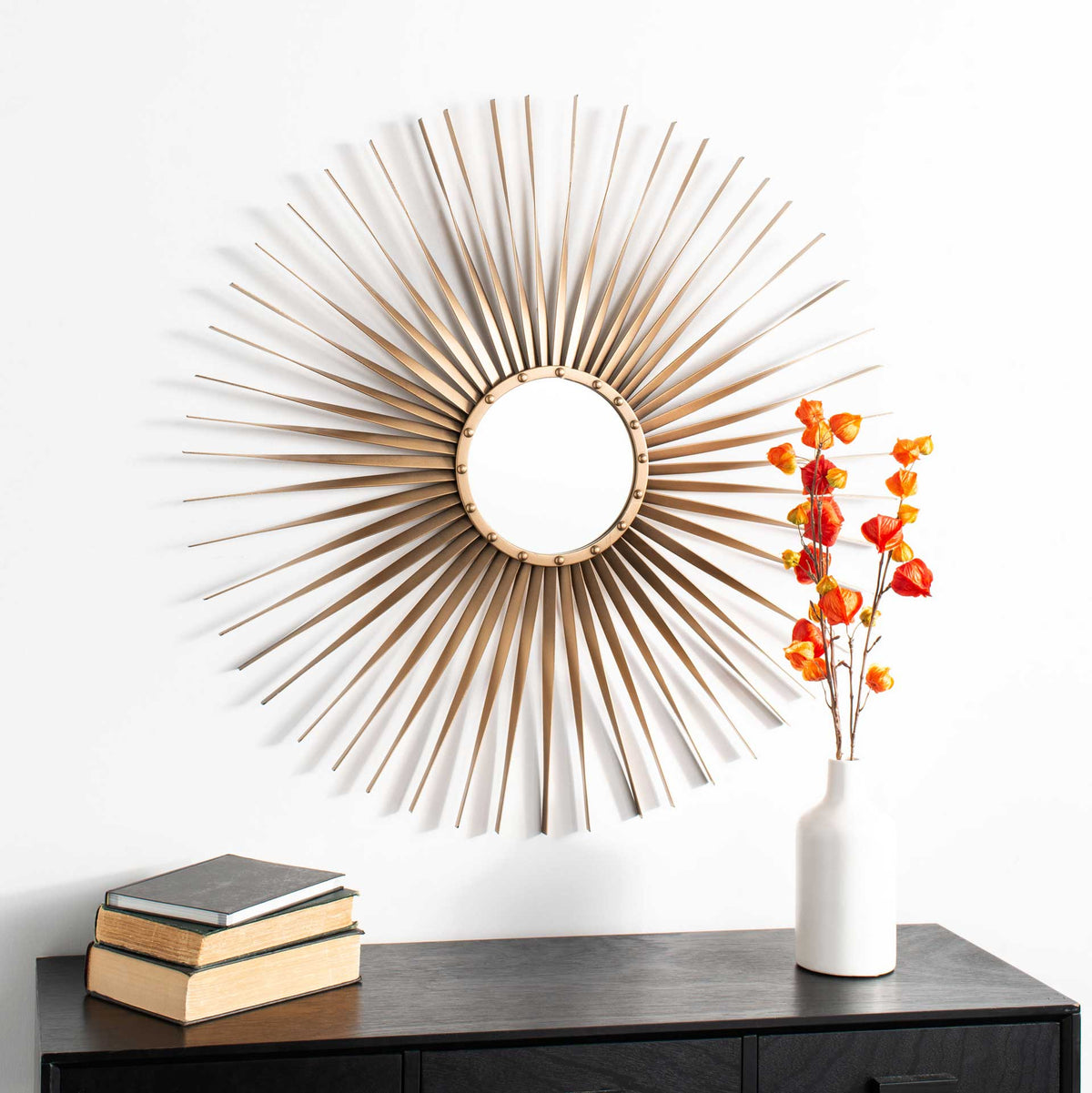 A gold sunburst mirror adds sculptural warmth and a striking focal point above a console