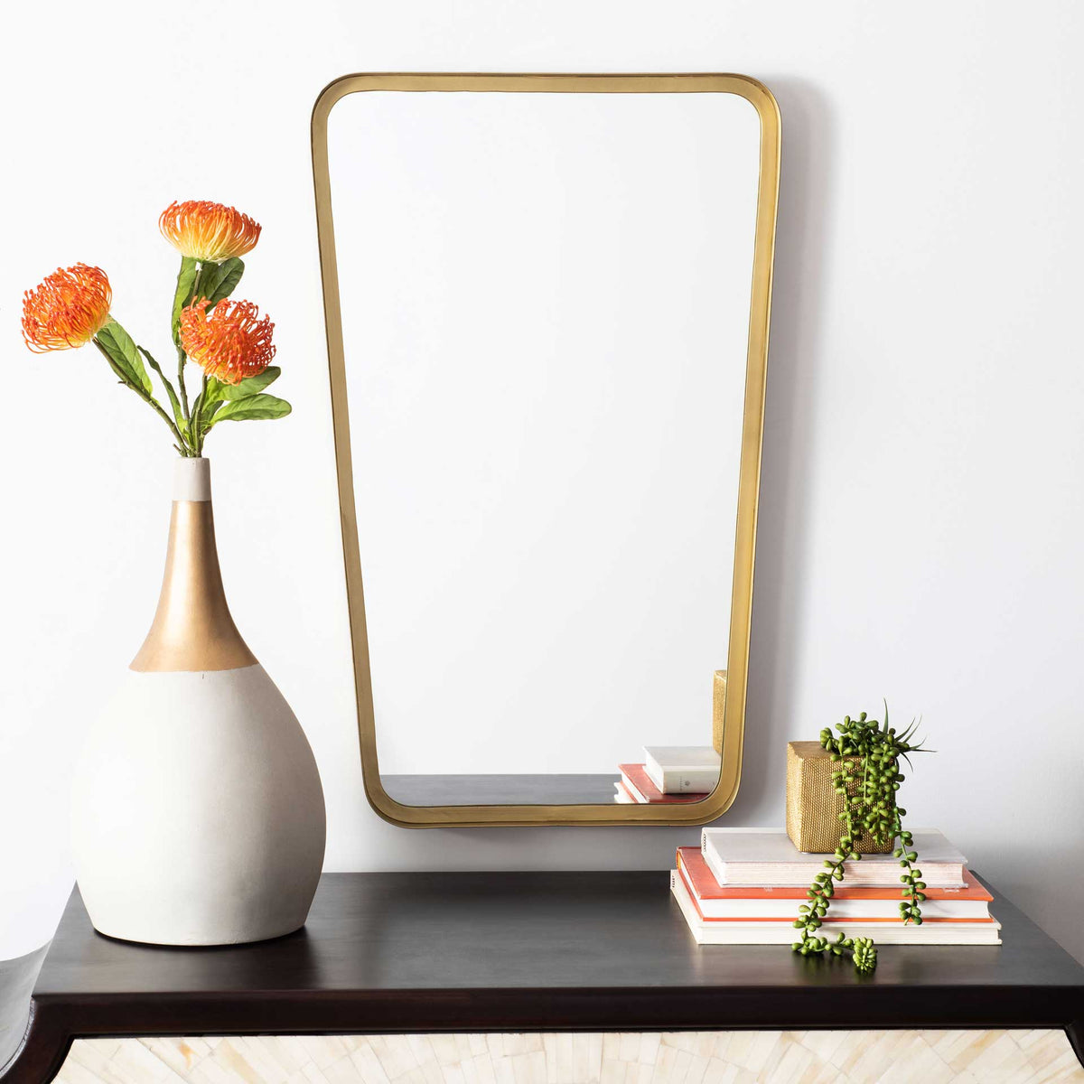 A brass-framed mirror adds warm, modern style above a console table