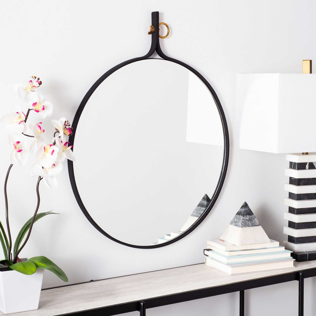Round black-framed mirror adds a bright reflective accent above a console