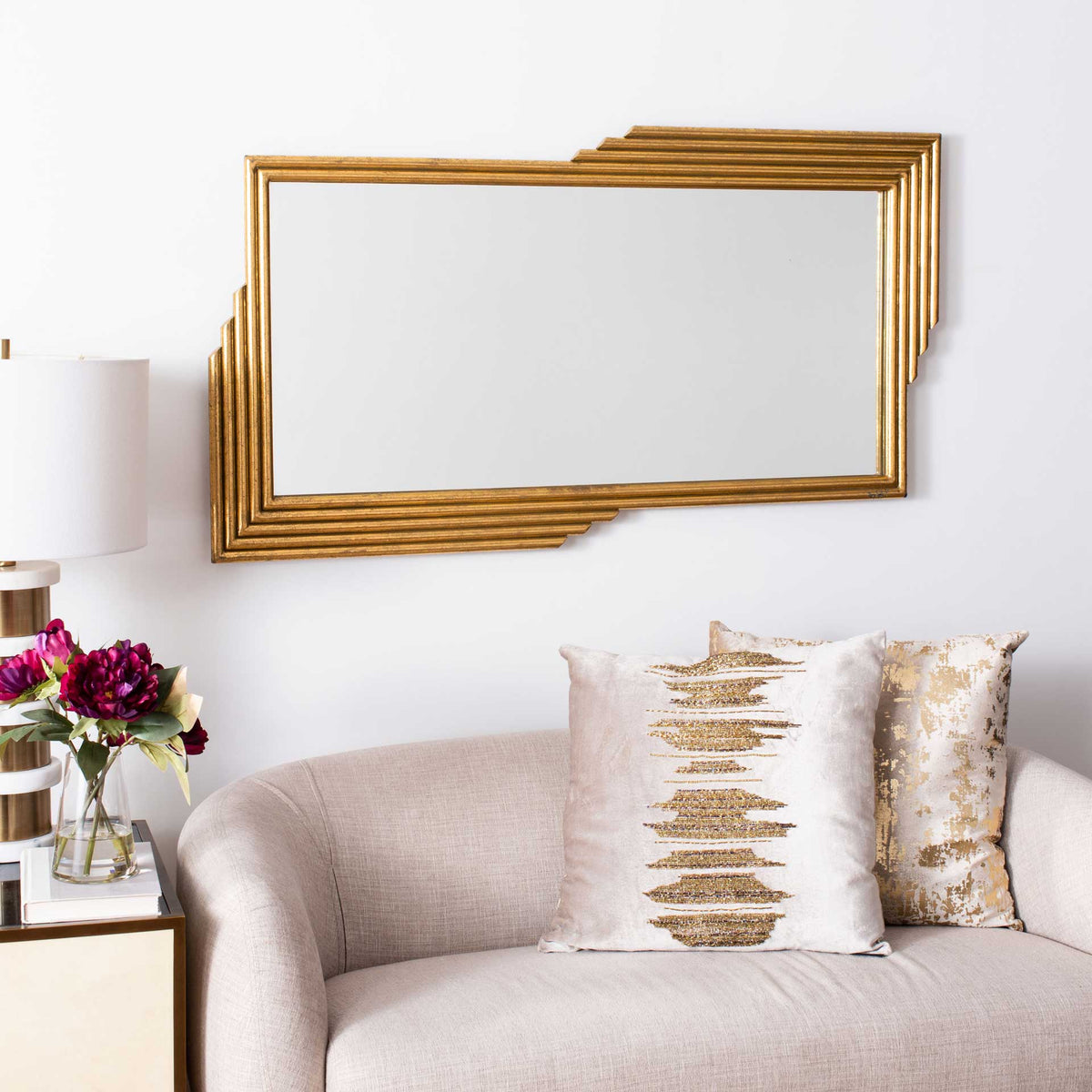 A wide wall mirror pairs reflective glass with offset, tiered gold framing.