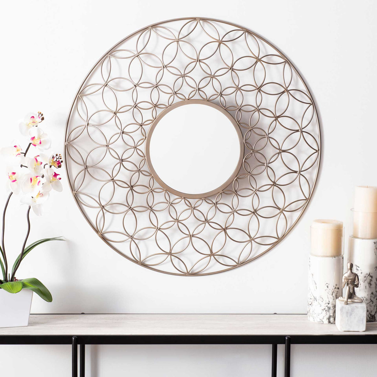 A champagne-toned round mirror adds an airy floral accent above a console table