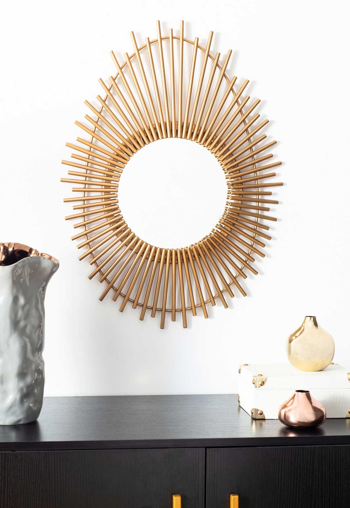 Gold sunburst mirror adds a radiant focal point above a dark cabinet