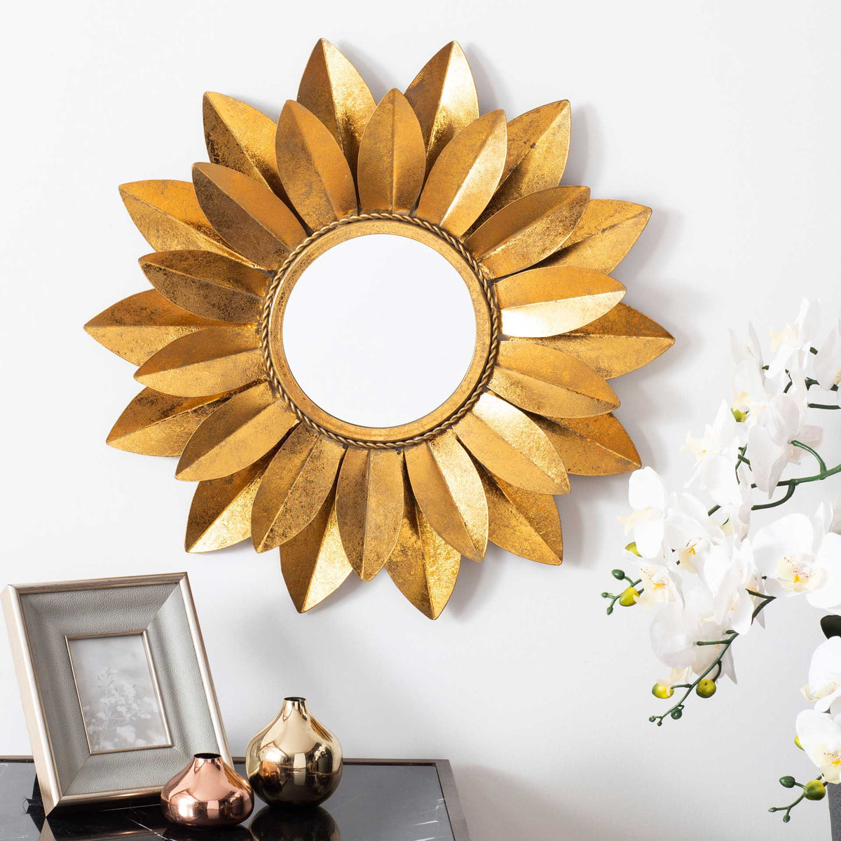 A gleaming gold sunburst mirror brings sculptural warmth to the wall above a console