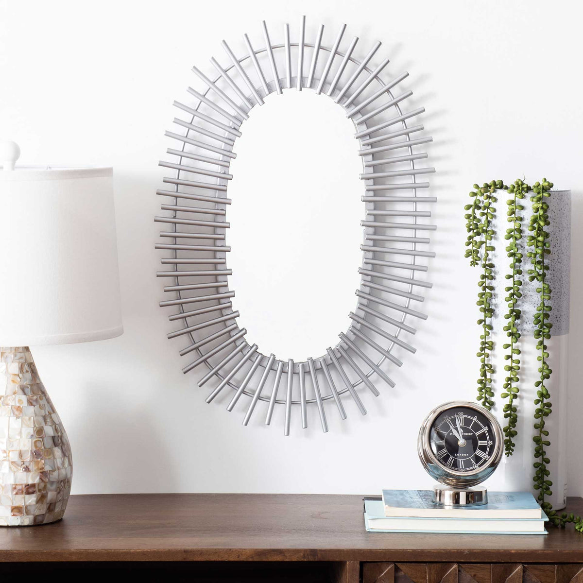 Layered silver rays frame an oval mirror, adding sculptural shimmer to any room