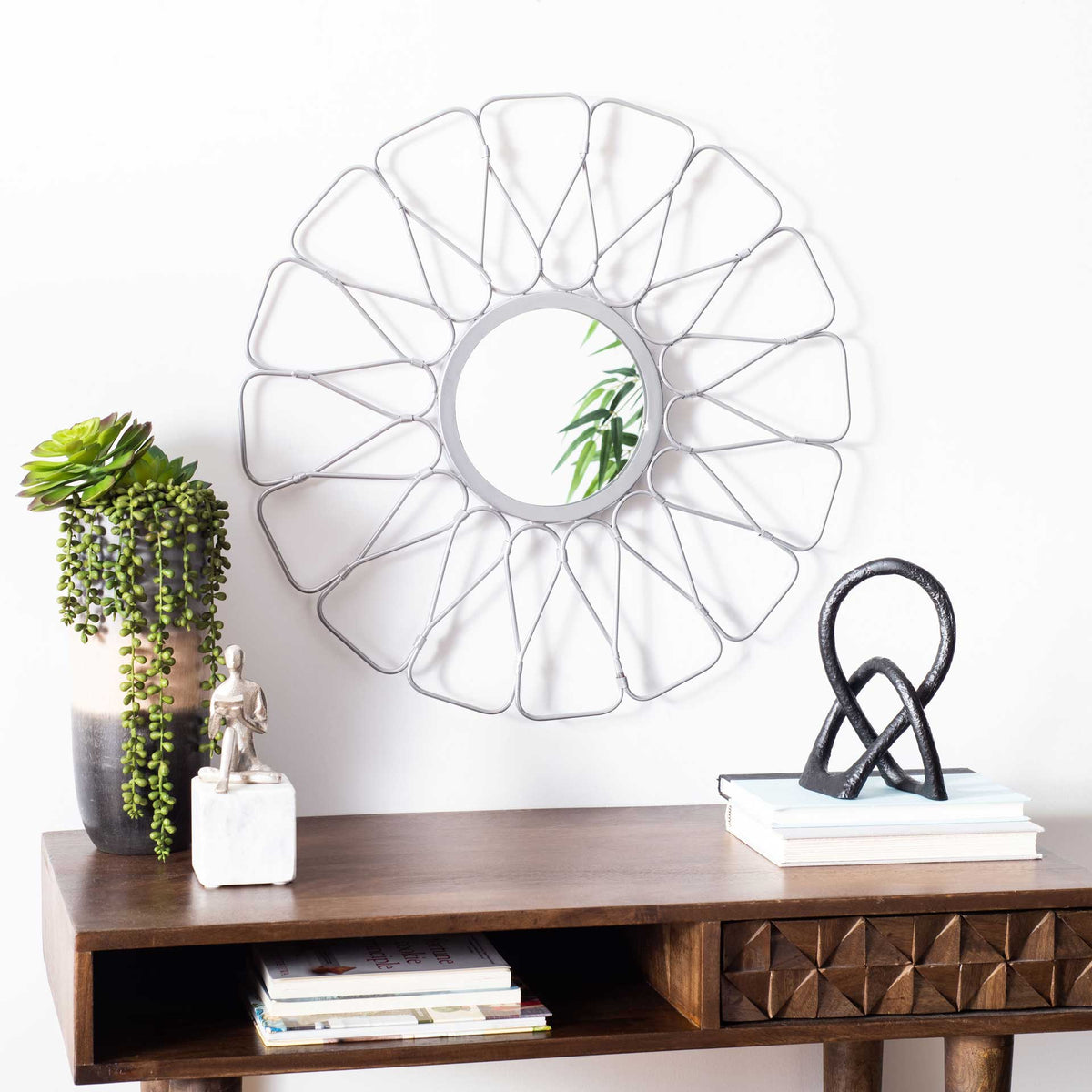 Openwork silver frame surrounds a round mirror, adding a floral accent above a console