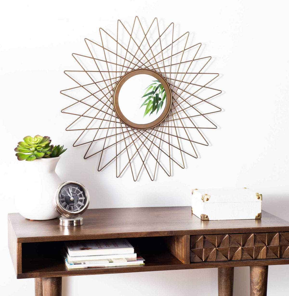 An openwork gold starburst design gives this round wall mirror sculptural shine