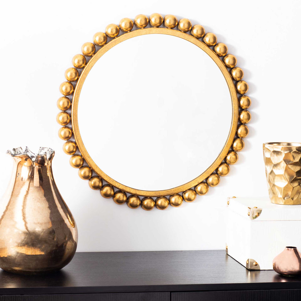 Gold beaded round mirror adds a warm decorative accent above a dark console