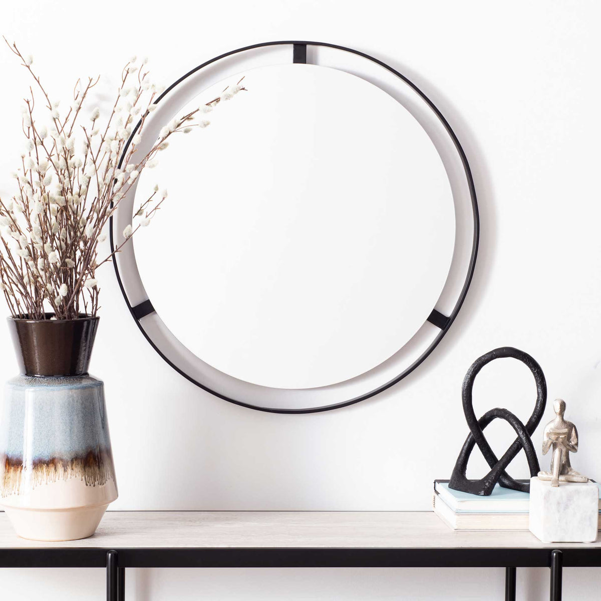 Round mirror with an open dark metal ring adds modern contrast above a slim console