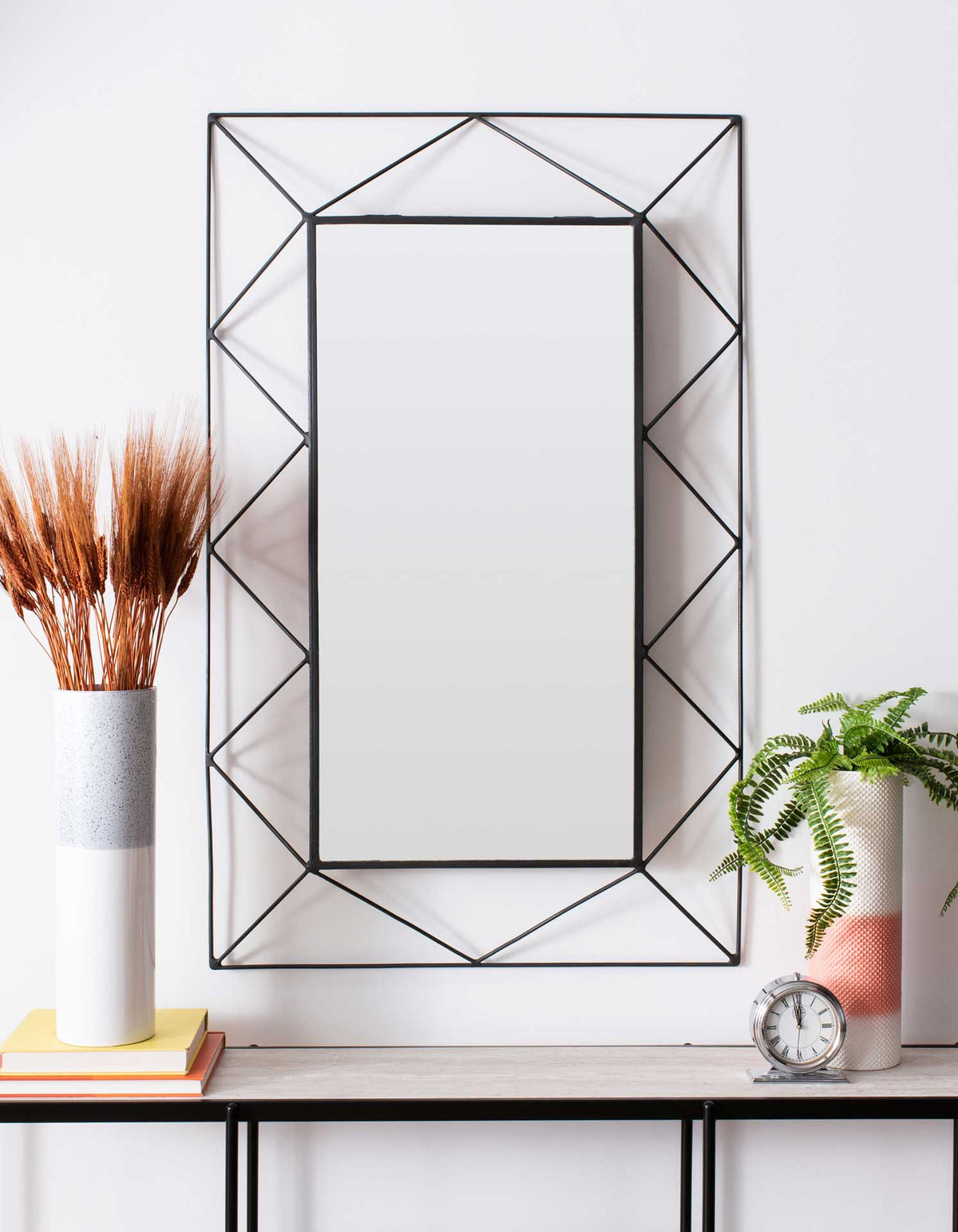 An airy geometric frame gives this rectangular wall mirror a modern decorative touch.