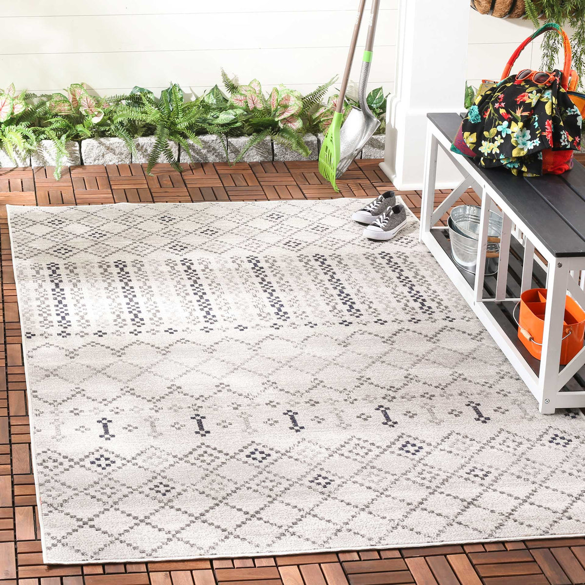 A gray geometric rug adds patterned warmth to a patio with its diamond motifs and charcoal stripes.