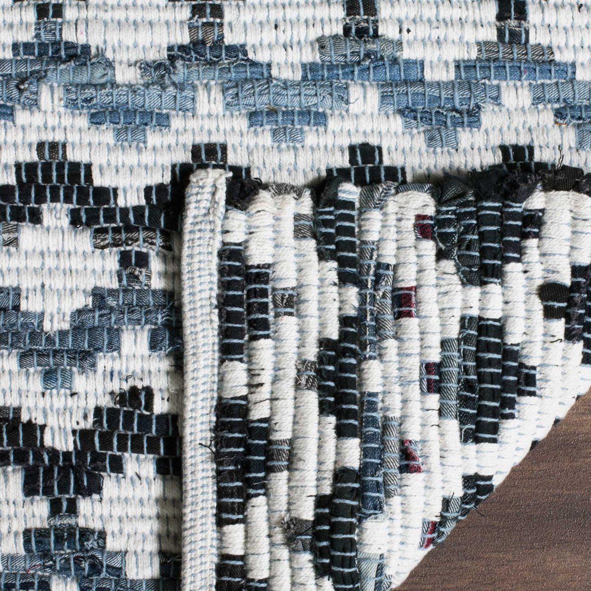 Folded ivory rug corner exposes its densely woven black and blue underside