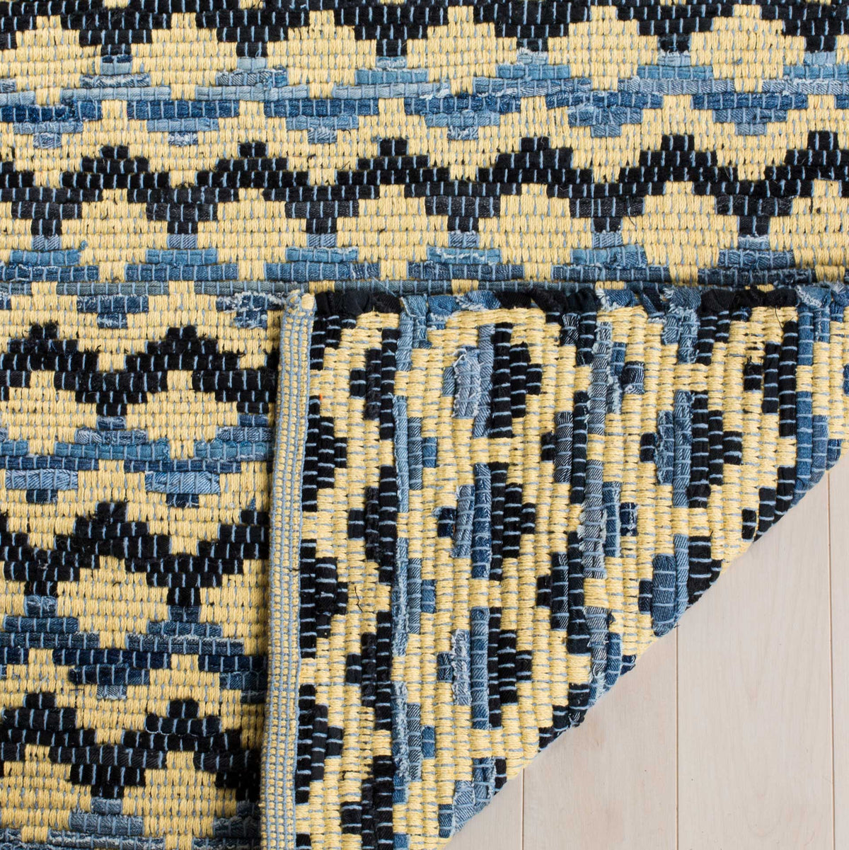Folded rug corner exposes a richly patterned blue, gold, and black woven underside