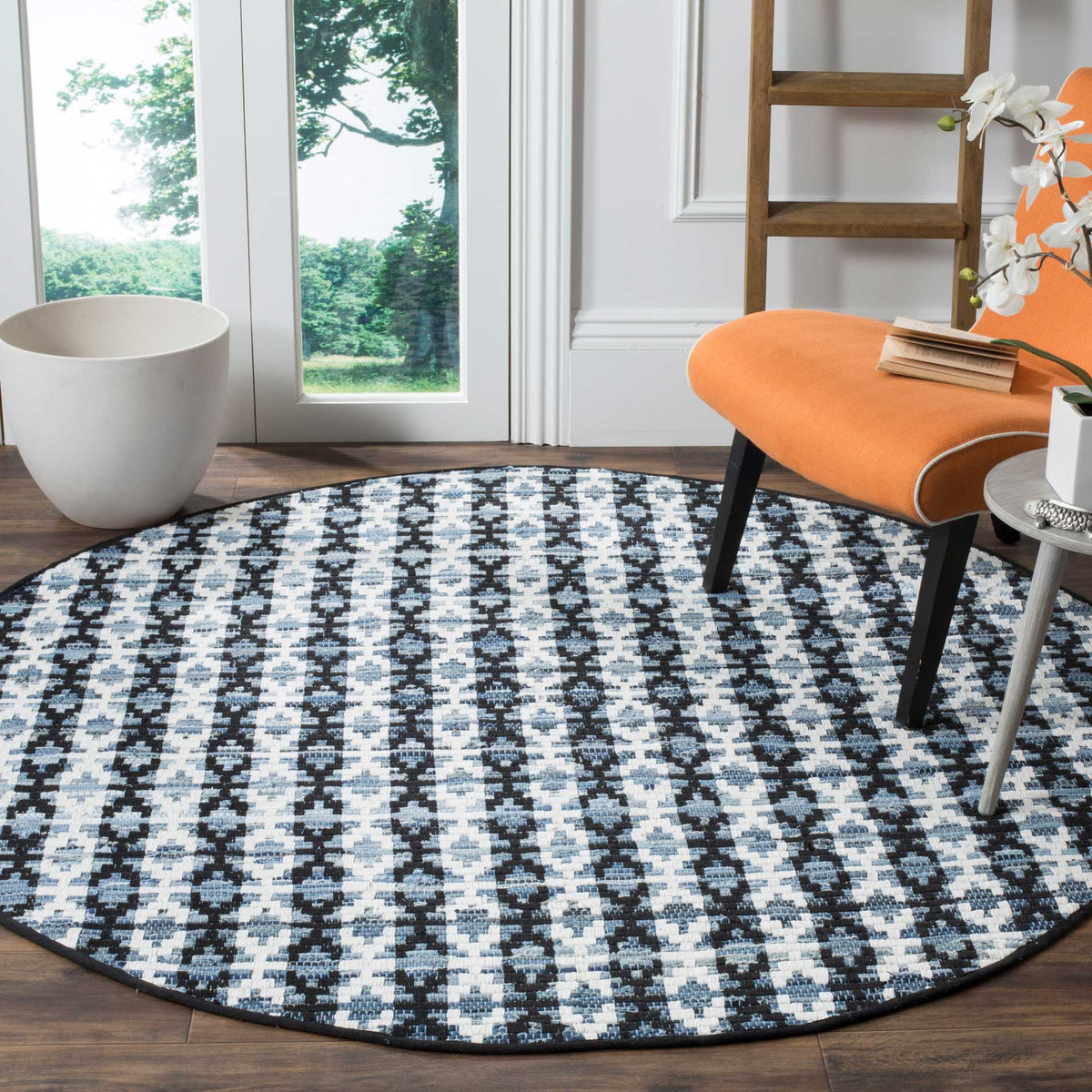 Black, blue, and ivory round rug grounds a bright seating area with bold geometric contrast