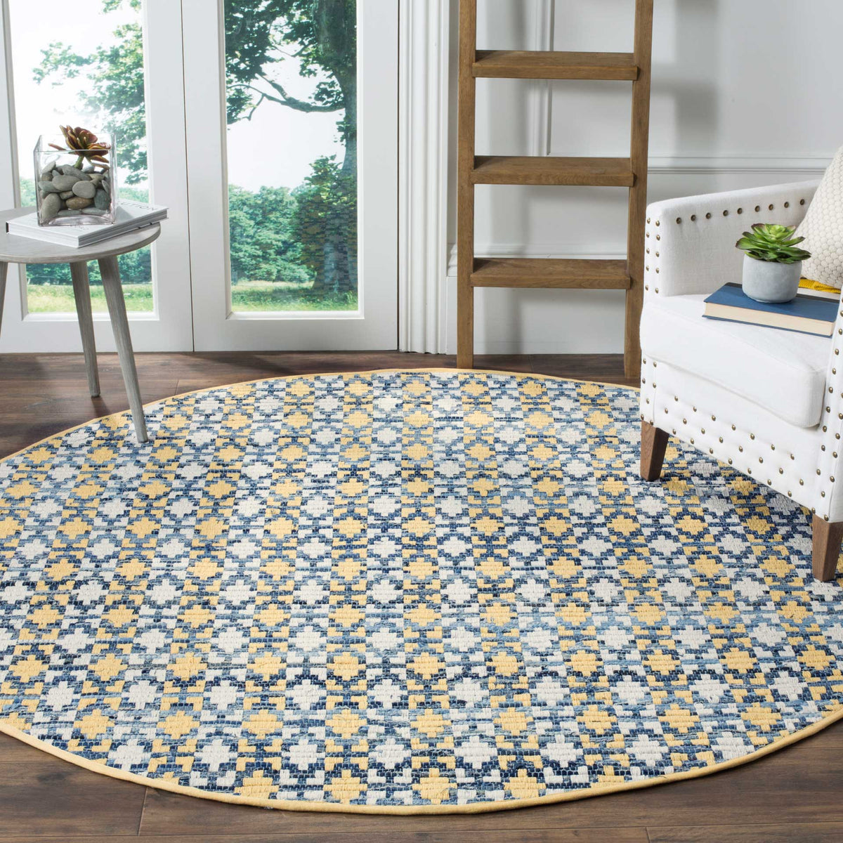 Gold and blue geometric rug brings warm color beneath a white accent chair and side table