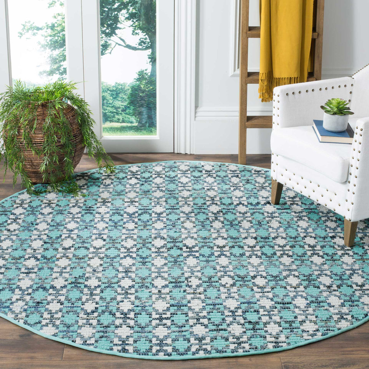 Turquoise and blue round rug adds fresh geometric texture beneath a white accent chair
