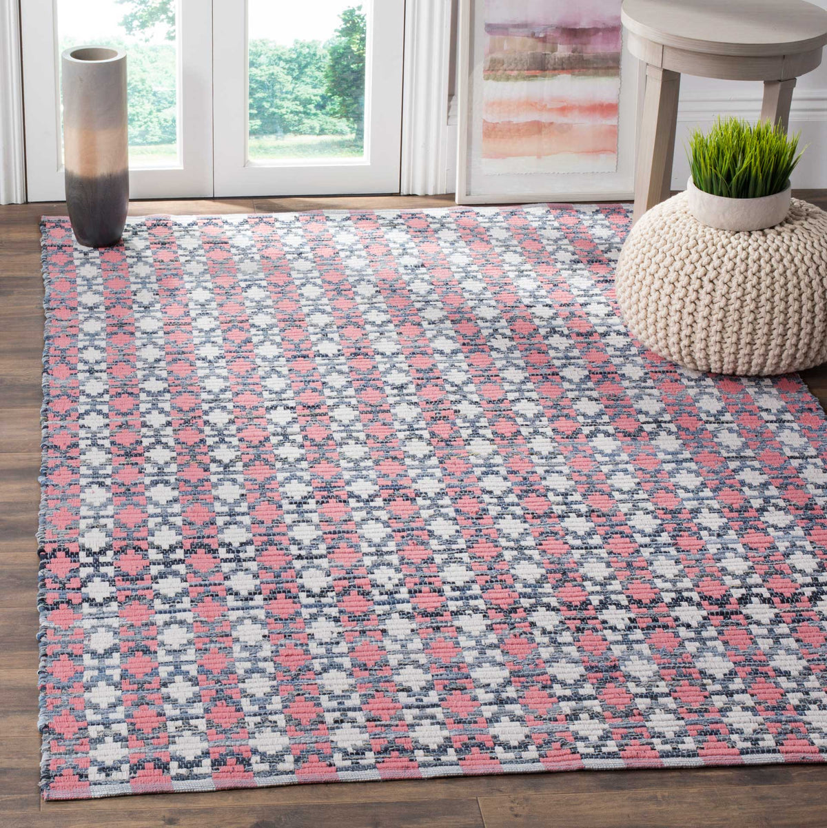 Coral and blue geometric cotton rug adds a vivid accent beside wood flooring and neutral furnishings