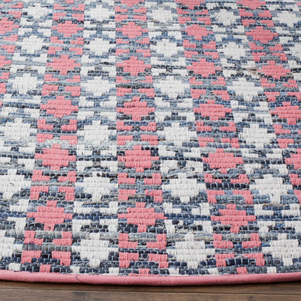 Coral motifs pop against a textured blue-and-ivory weave with a neatly bound pink edge