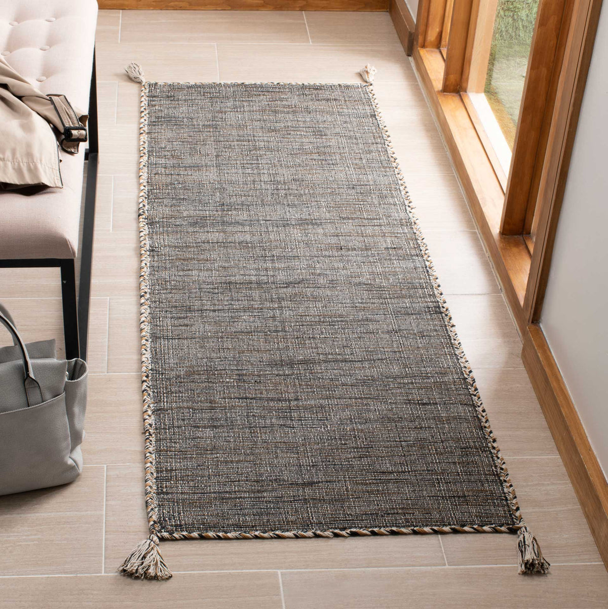 Subtle beige and black threads give this slim cotton runner a relaxed texture and tasseled corners