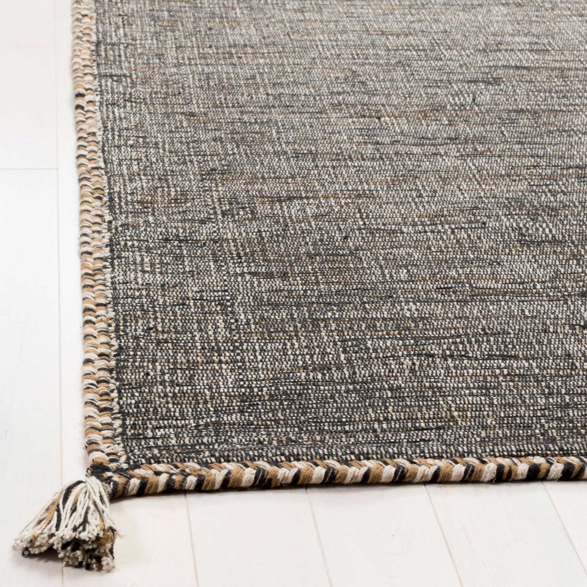 Twisted beige and black edging frames the textured cotton weave, finished with a corner tassel.