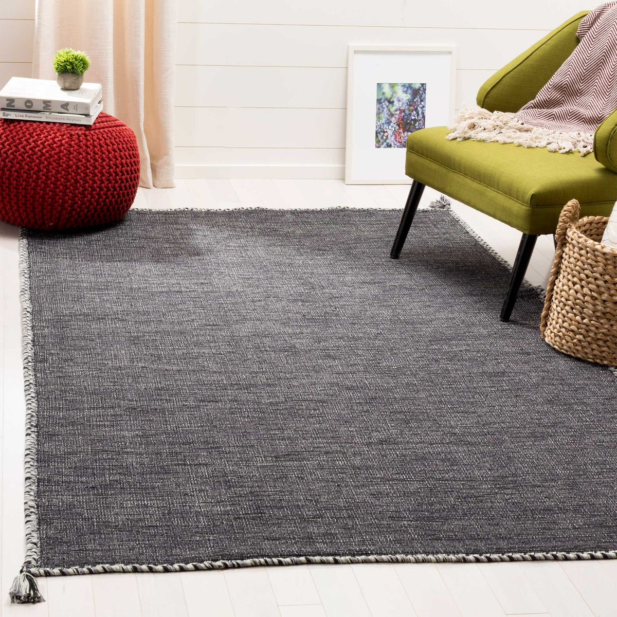 The gray and black cotton rug grounds a seating area with fine texture and a braided border.