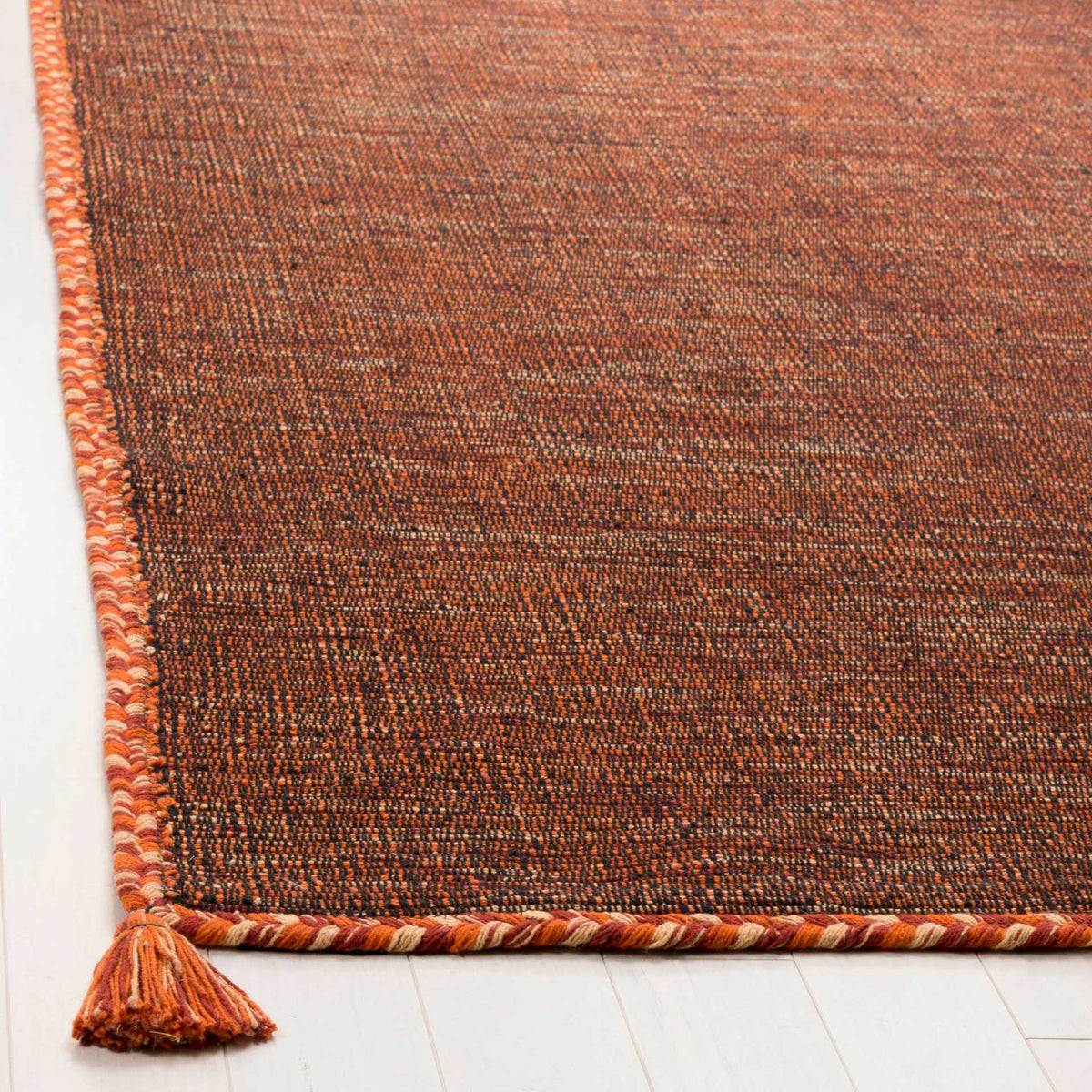 Twisted orange and black trim and a bright corner tassel frame the textured cotton weave.