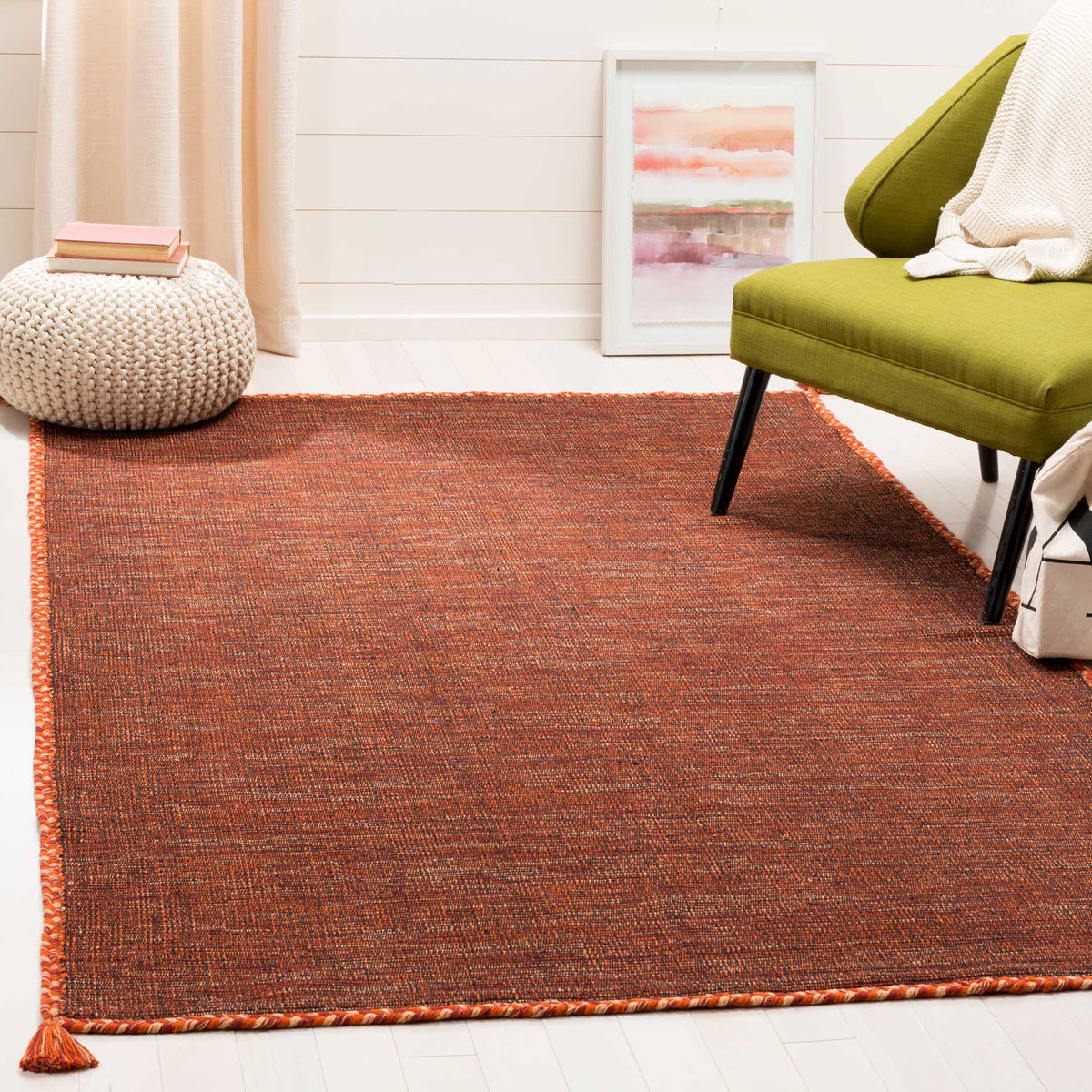 A vivid orange and black cotton rug adds warmth and texture to a cozy seating area.