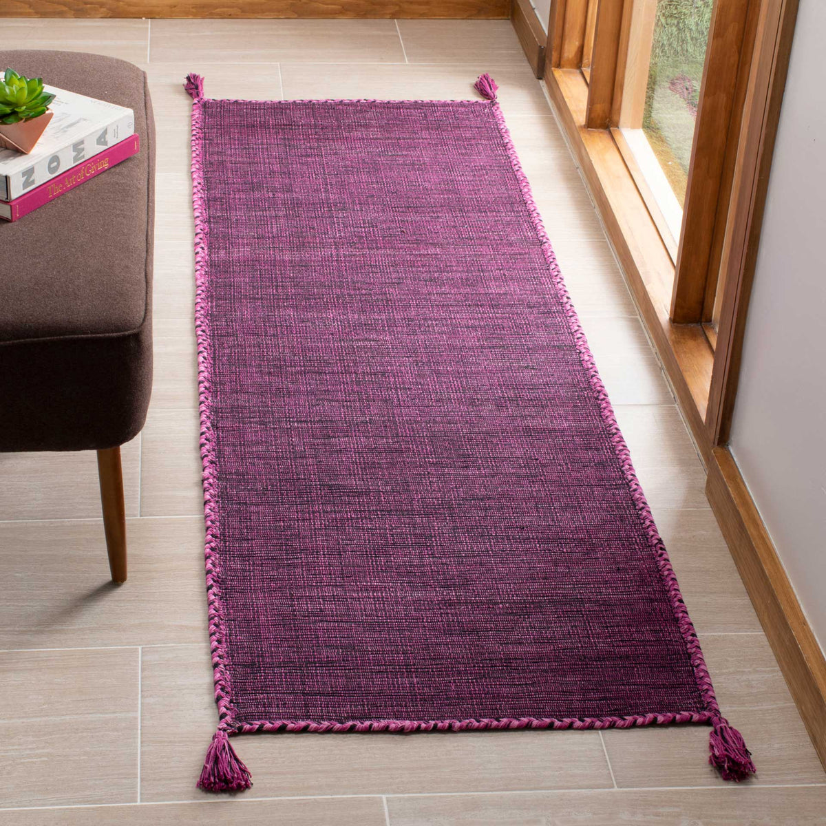 Vibrant purple and black threads give this low-profile woven runner depth, with braided trim and tassels