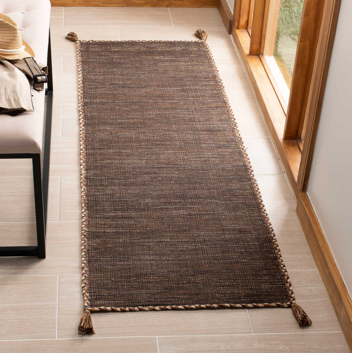 Earthy brown and black threads bring warmth to this low-profile runner with a braided edge and tassels