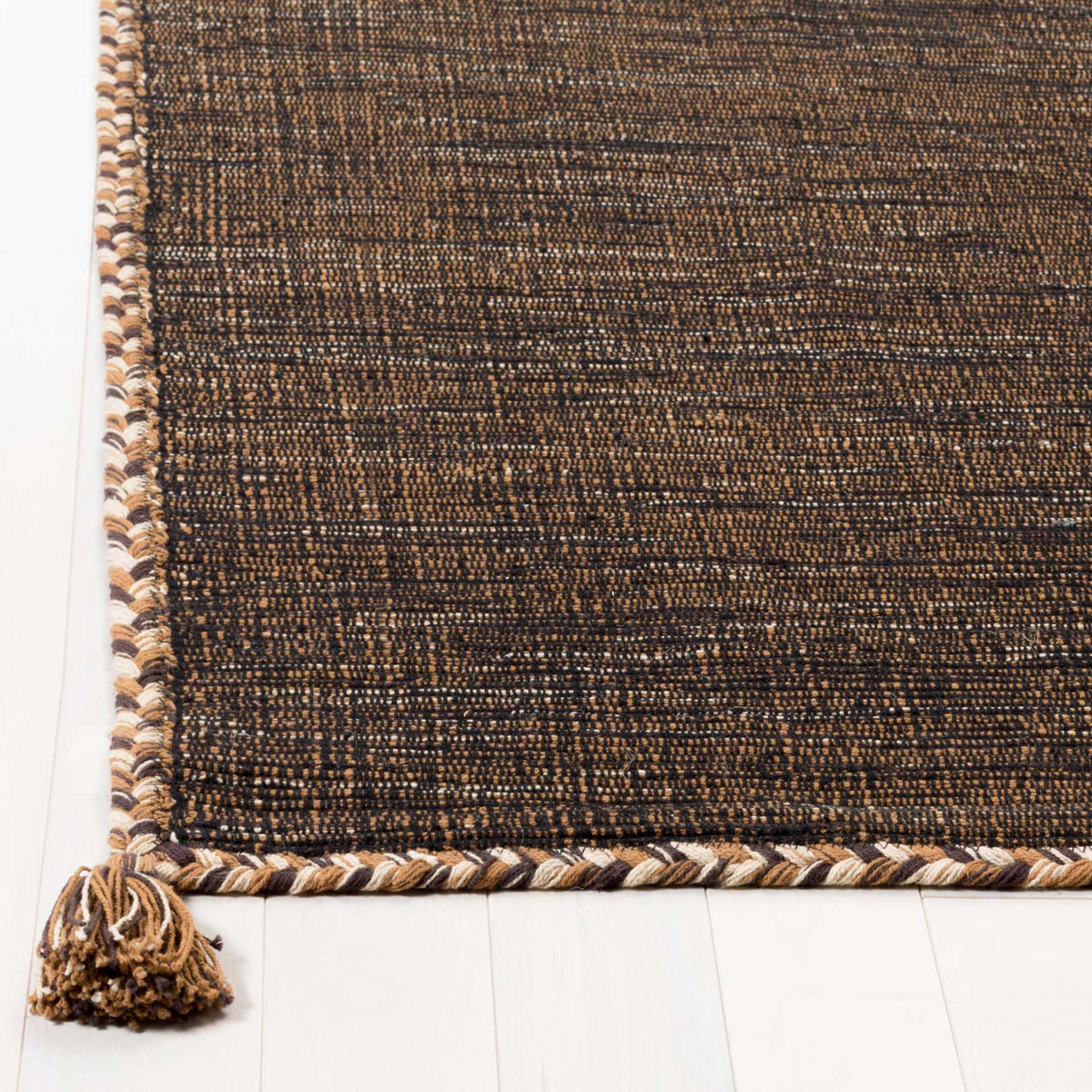 Braided brown and black edges and a thick corner tassel accent the closely woven cotton surface.
