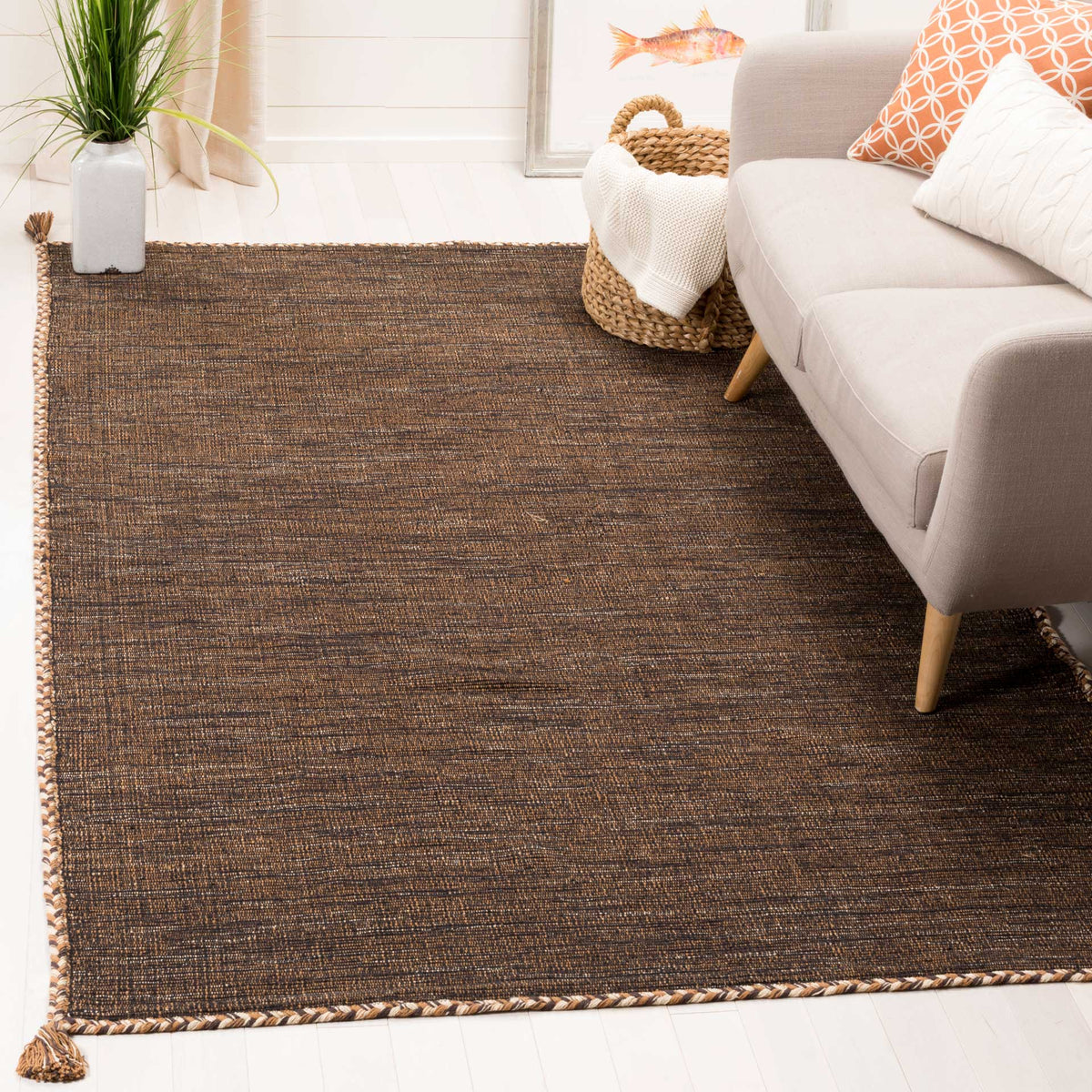 Warm brown and black tones give this flatwoven cotton rug a grounded look beside a sofa.