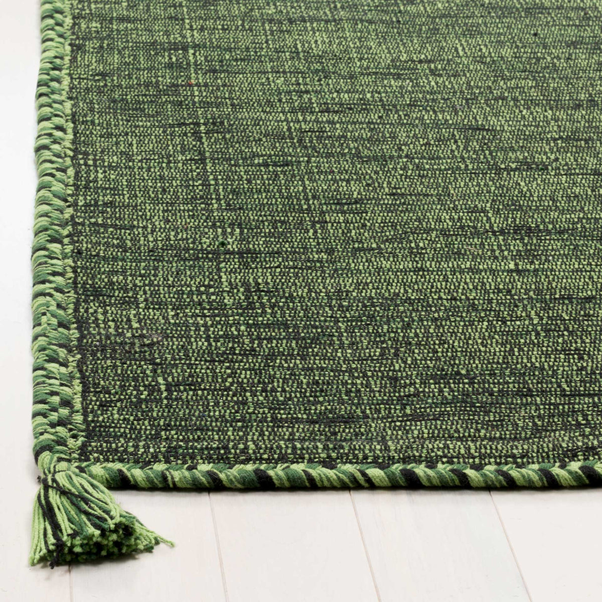 Green and black braided edges meet a textured cotton weave and a generous corner tassel.