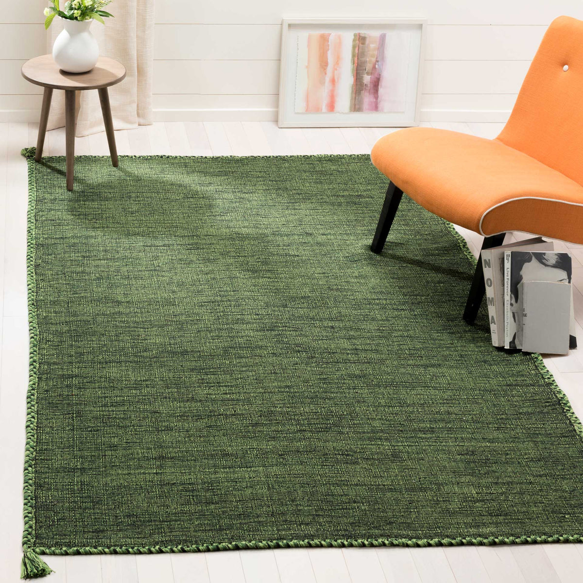 The green and black cotton rug adds earthy color and tactile texture beneath a lounge chair.