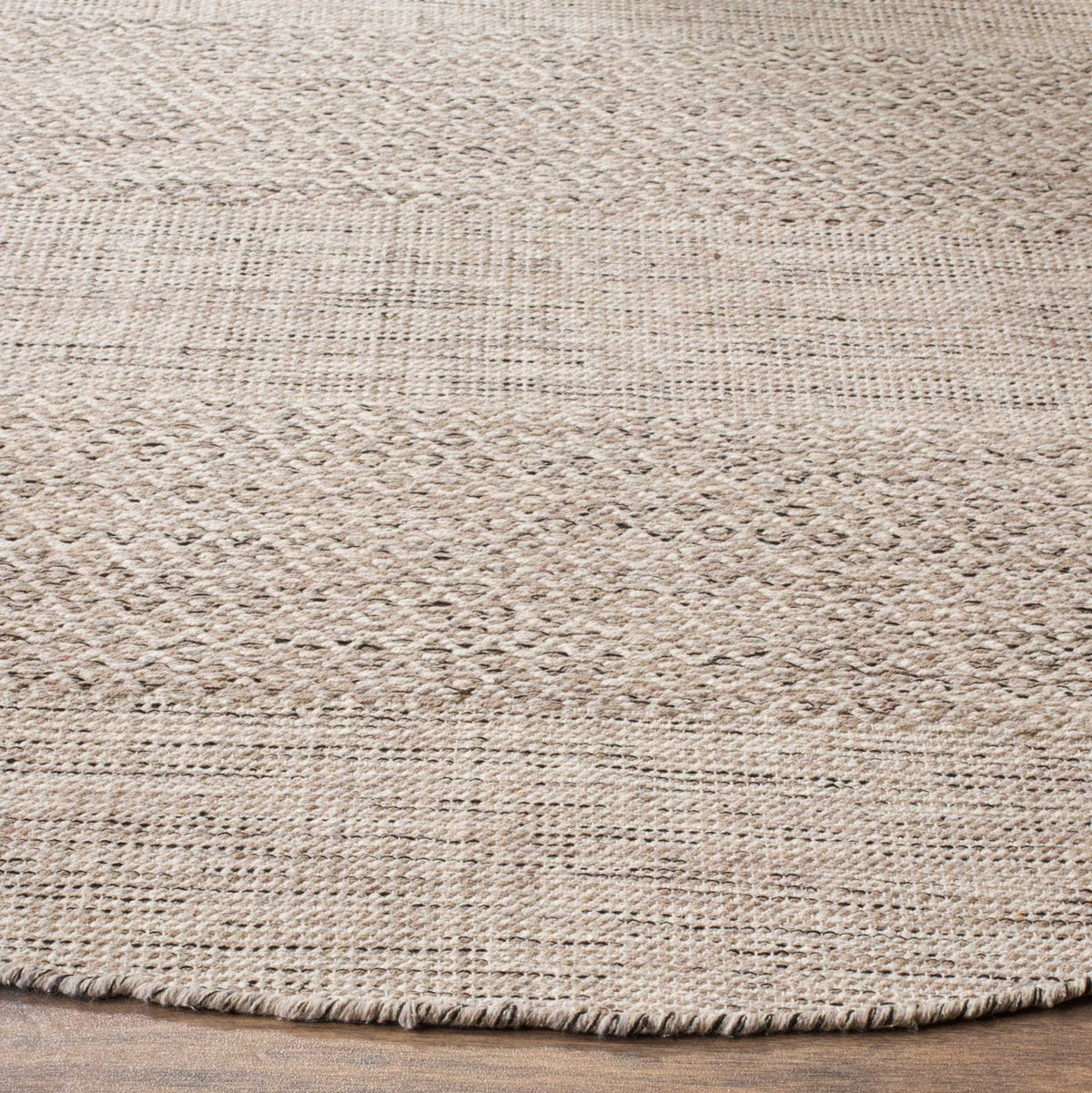 Softly textured ivory cotton and muted steel gray motifs frame the rug's finished edge