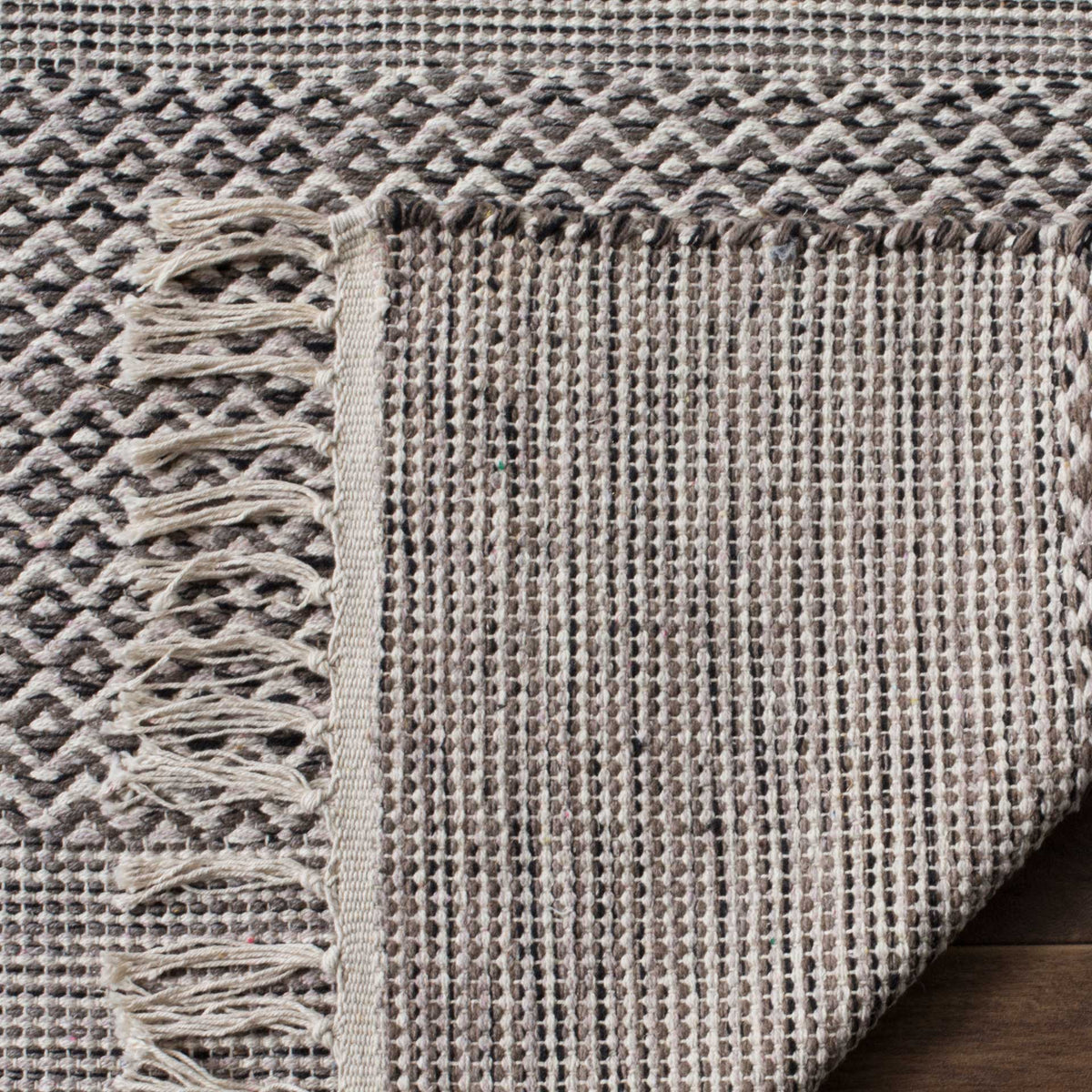 Folded cotton edge reveals a tightly woven backing beneath anthracite and ivory motifs