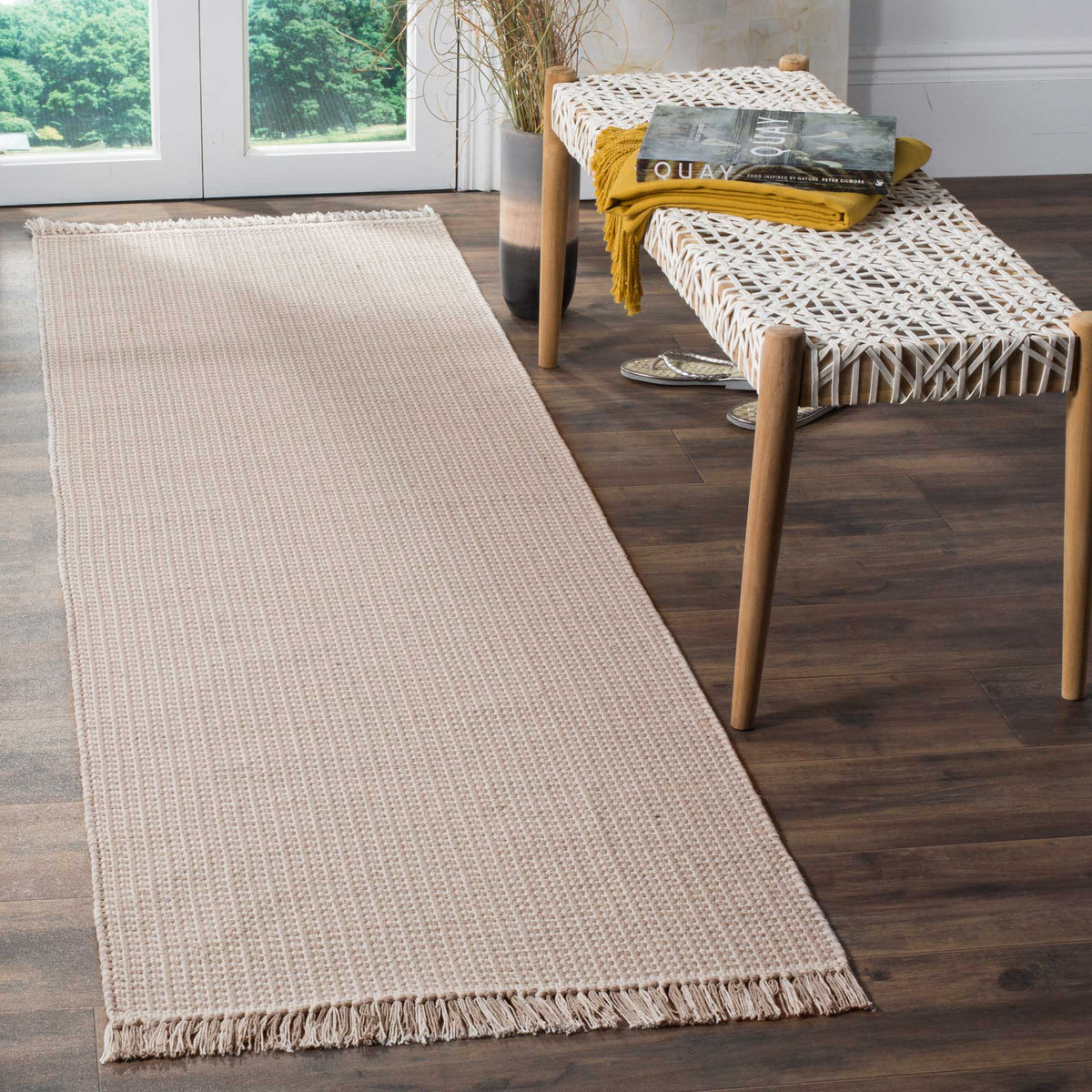 A muted ivory and gray weave brings gentle texture and understated fringe to this runner