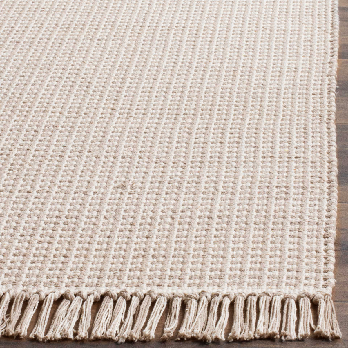 Soft gray and ivory cotton yarns form a raised grid above a generous tasseled edge