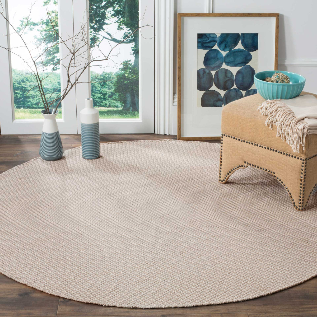 Low-profile ivory and gray round rug brings quiet texture to a bright sitting area