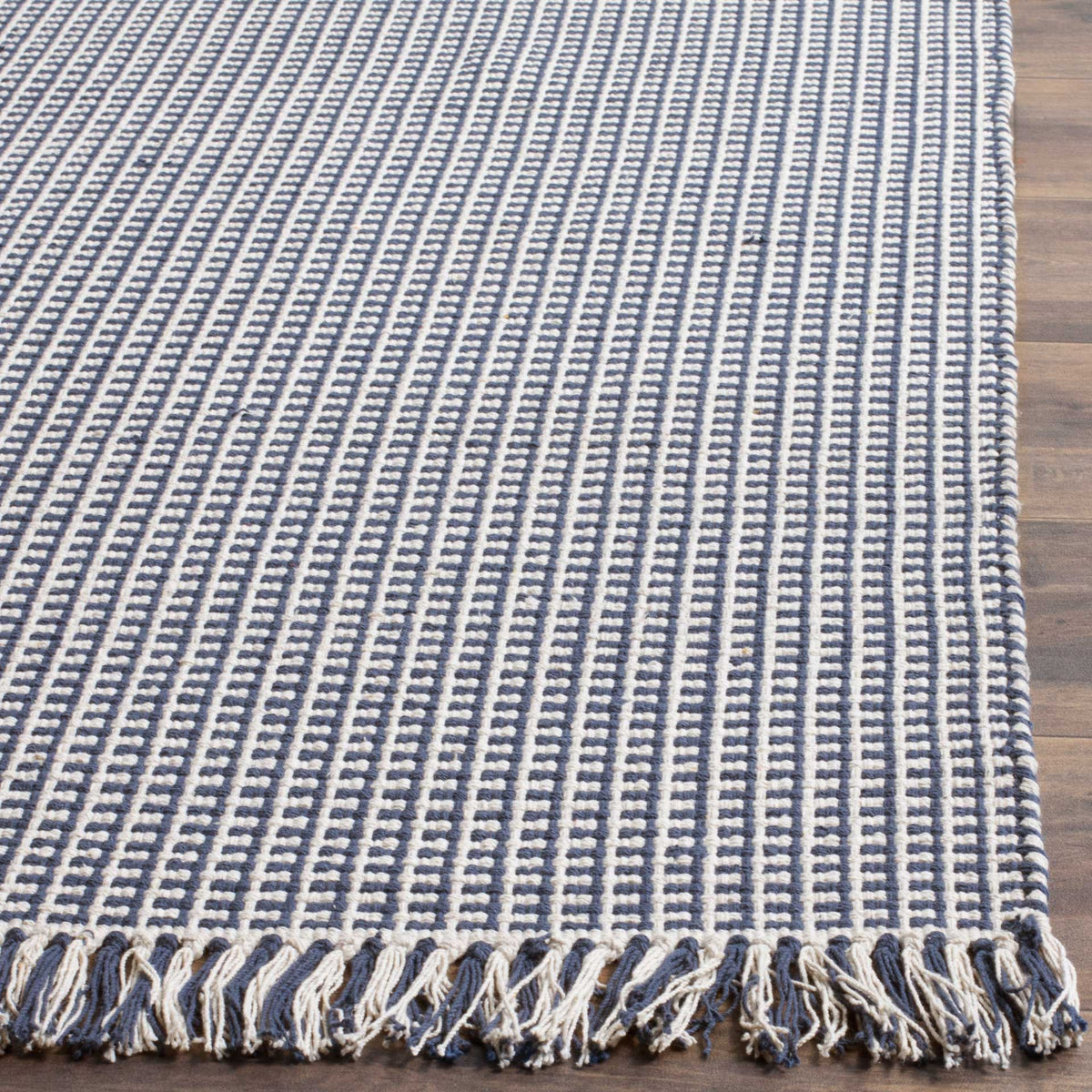 Alternating navy and ivory cotton loops form a bold grid above two-tone tassels