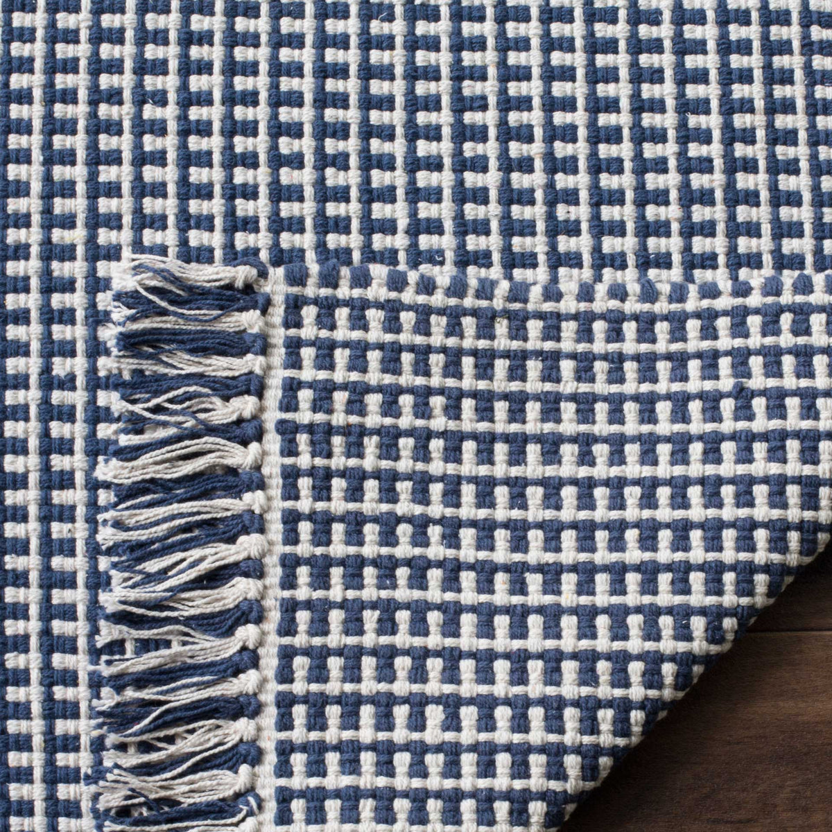 Navy and ivory cotton rug has a tightly woven underside and mixed-color fringe