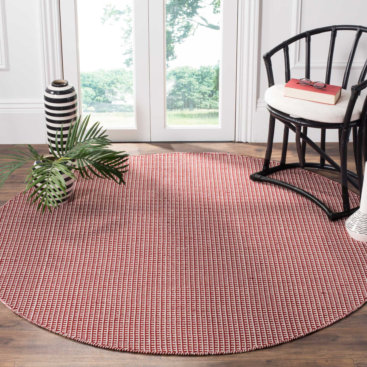 Vibrant red and ivory round rug brings a woven accent to a bright seating area
