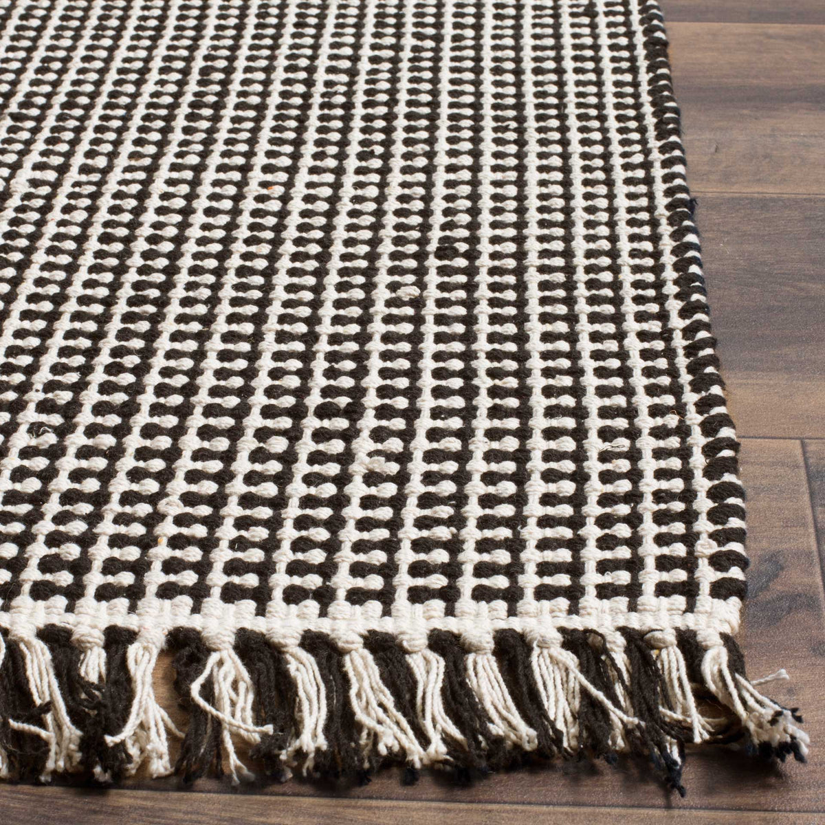 Black and ivory woven loops meet a contrasting fringe along the rug's edge