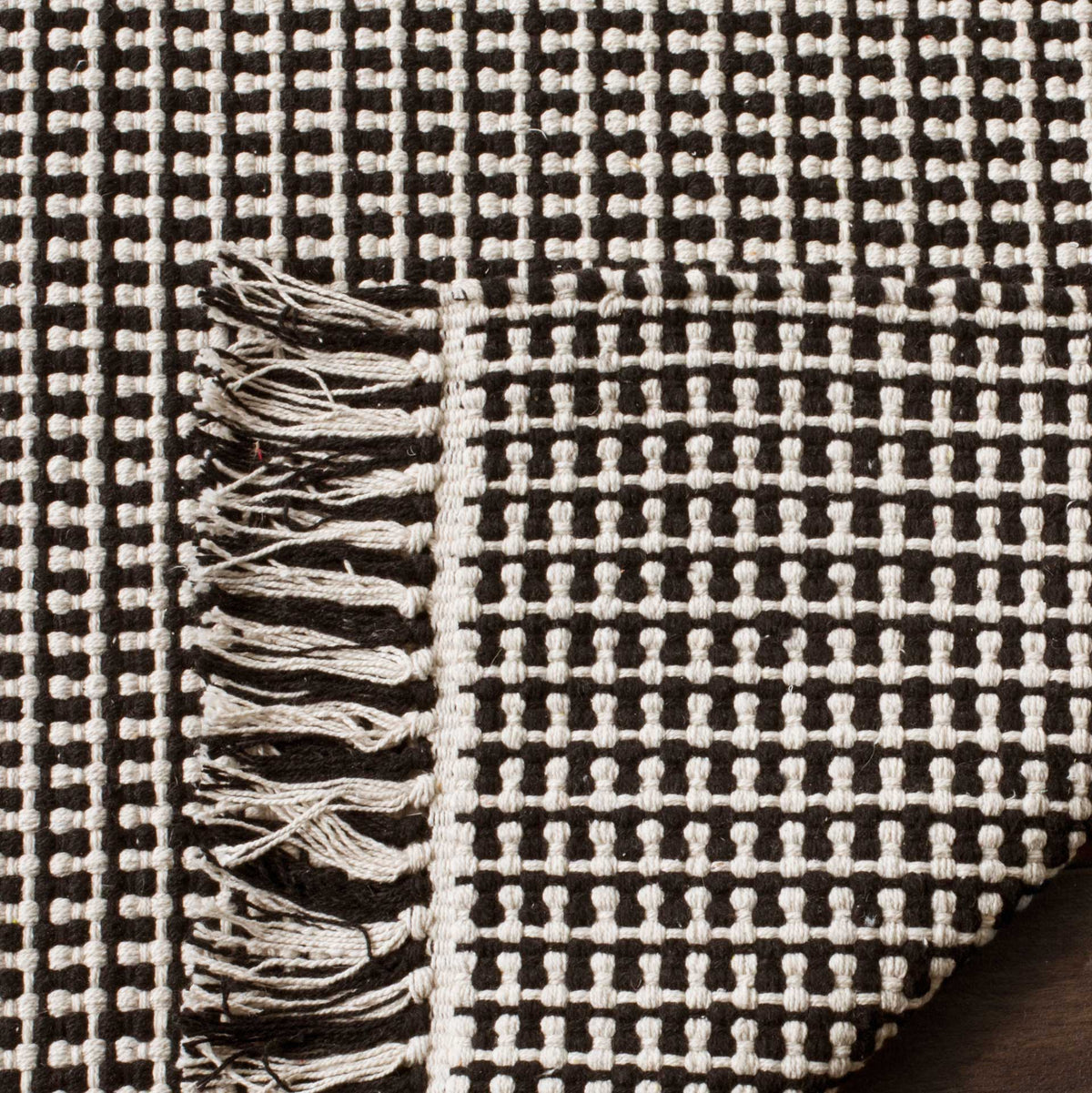 Black and ivory cotton rug has a closely woven underside and tasseled edge