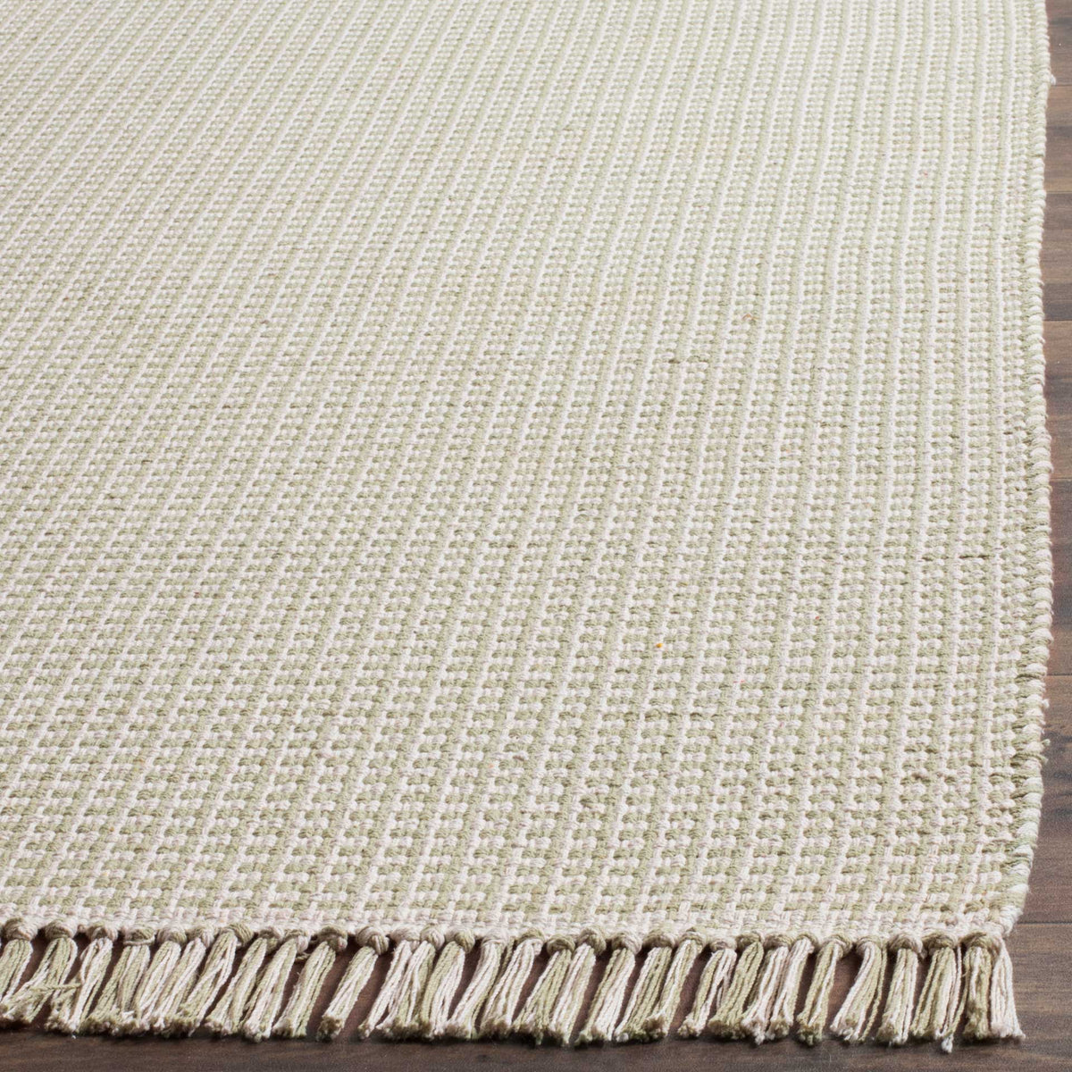 Pale green yarns cross ivory threads in a textured rug finished with a loose fringe